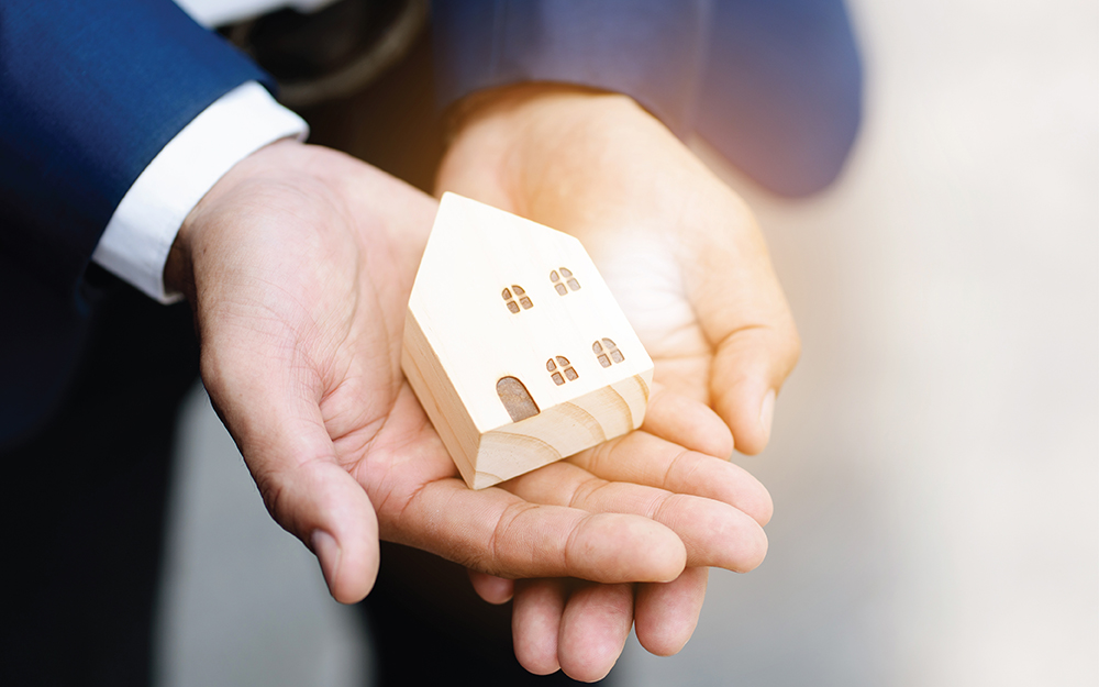 Hands holding a small home model